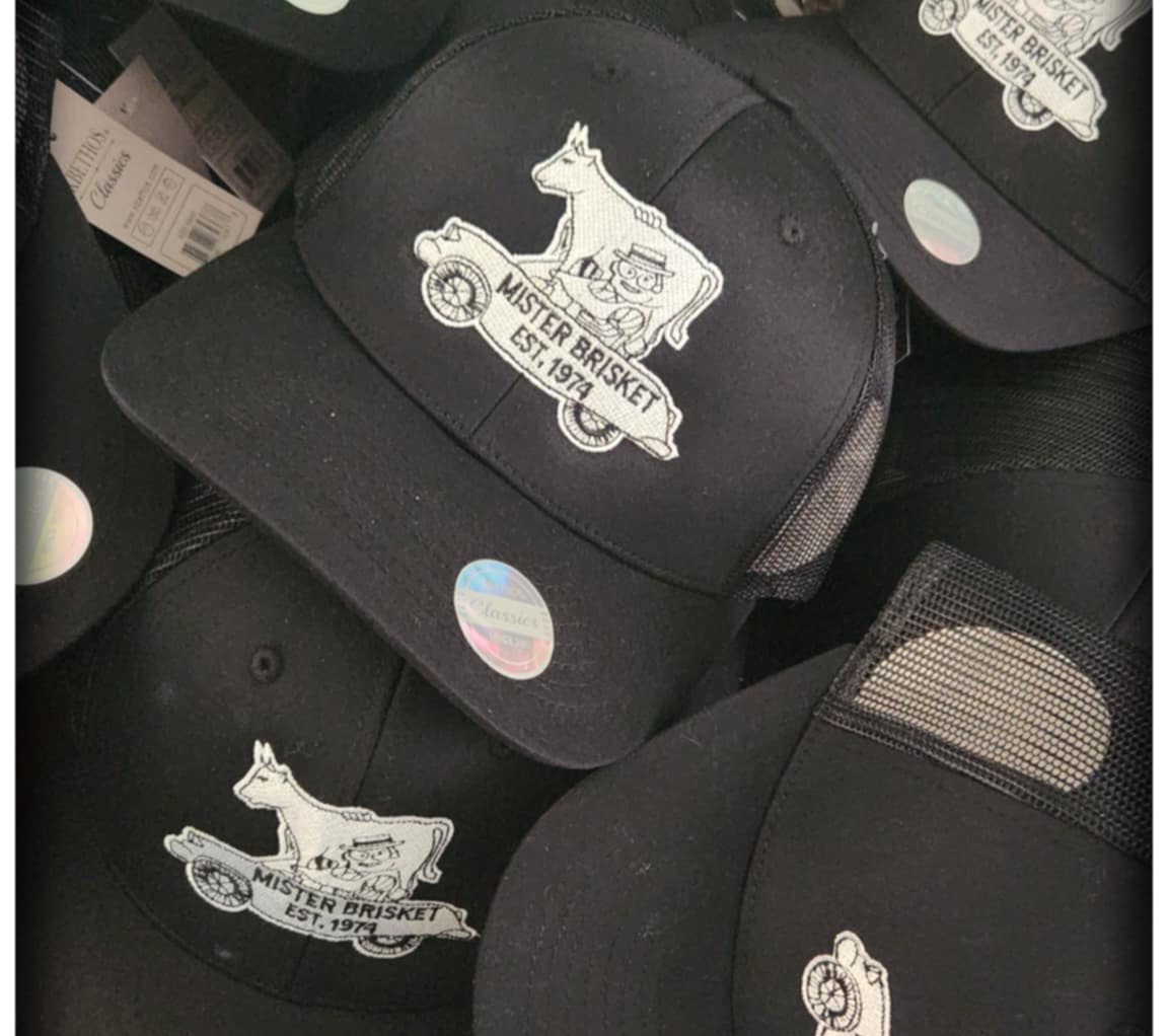 Mister Brisket Hat. Available in black with a black and white logo on the front. Snapback design allows for one size fits most.